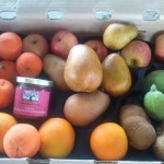 CSA box filled with pears, apples, feijoa, oranges, apples, and a jar of conserve.