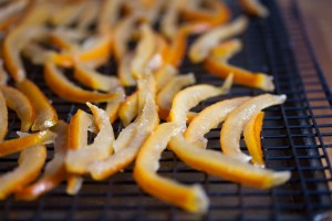 A closeup view of candied orange peels cooling on a wire rack.