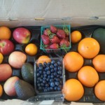 CSA Box filled with blueberries, strawberries, apples, oranges, tangerines, and avocados
