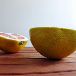 Photo of pomelo halves resting on a wooden table.