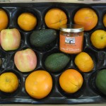 CSA Box with tangerines, oranges, apples, avocados, and a jar of apricot conserve